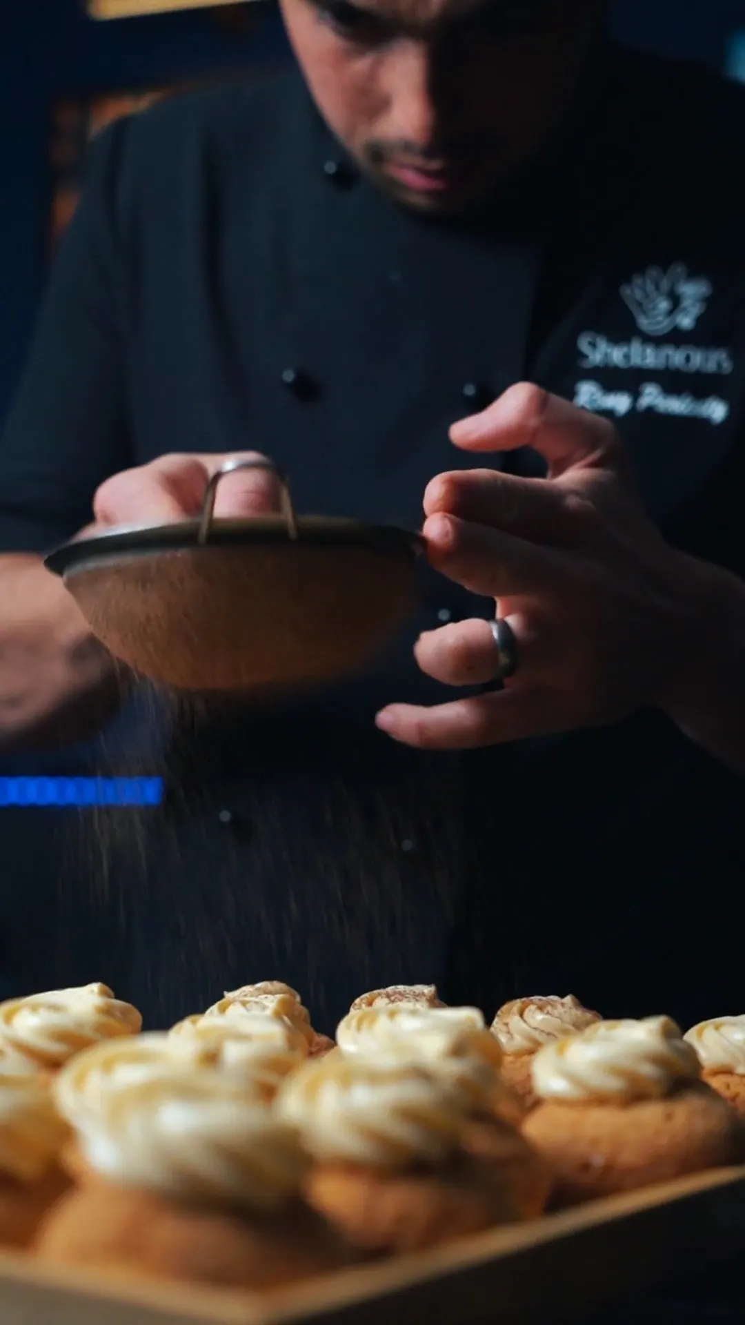 Chef Rony dusting a tray of cream tarts
