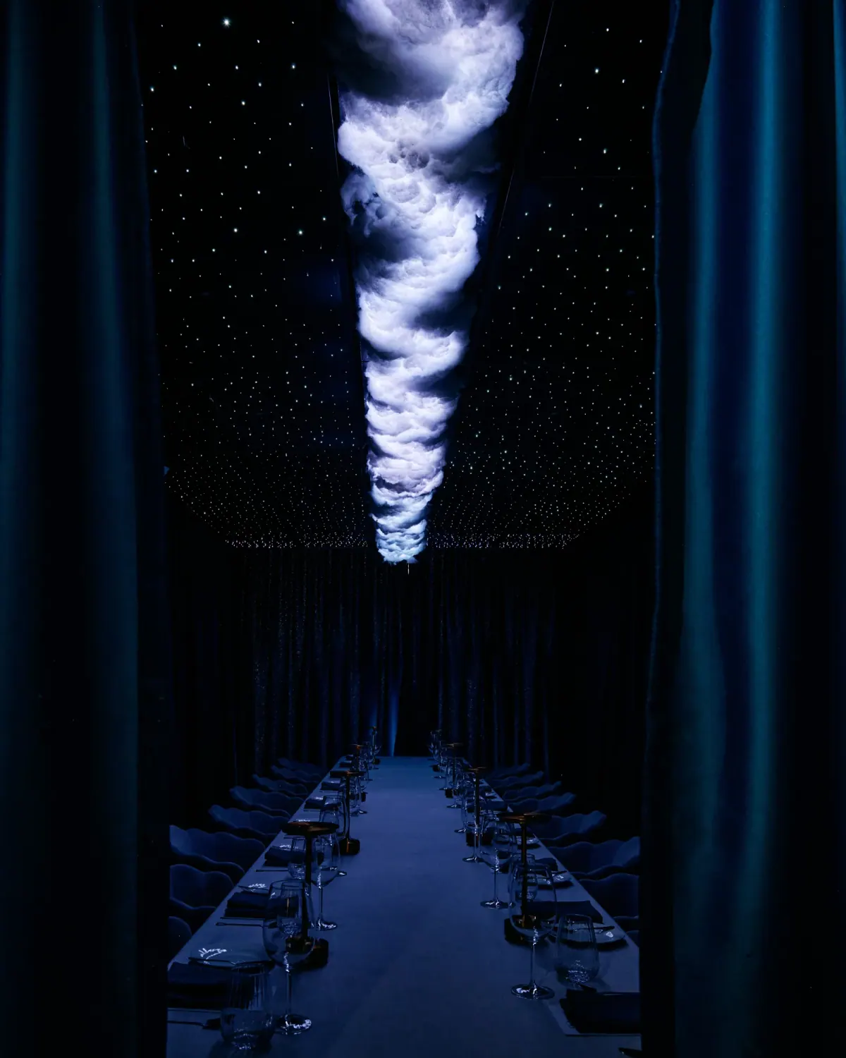 A swirling cloud above the long table in the darkened room